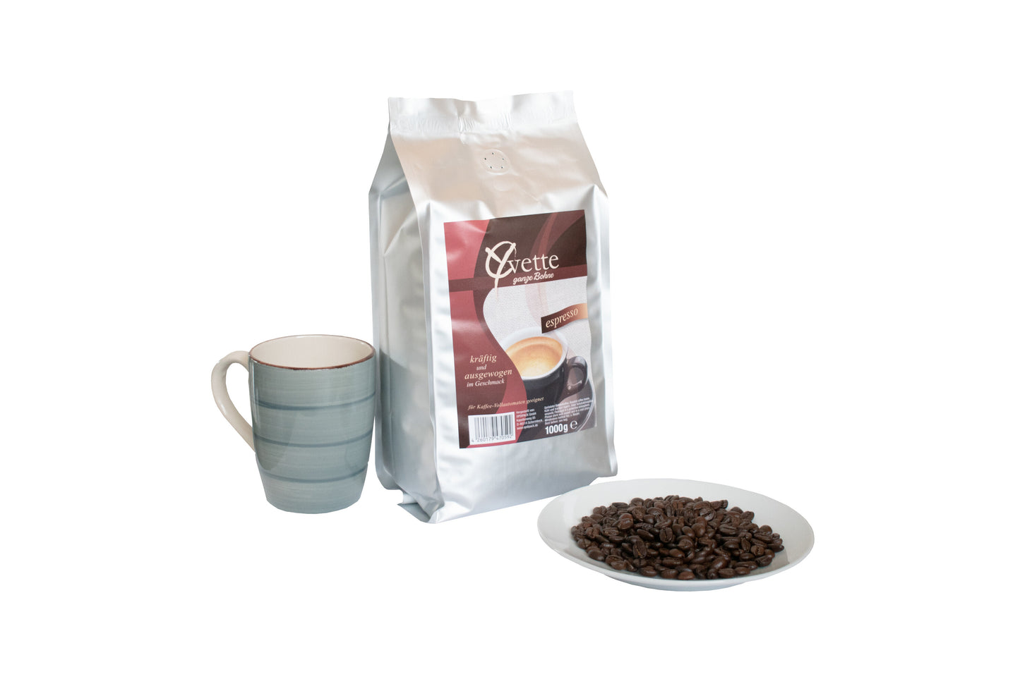 Ein silberner Beutel mit 1000g frisch gerösteten Espresso-Kaffeebohnen der Marke Yvette Kaffee. Der Beutel zeigt das Logo der Marke und die Produktbezeichnung. Vor dem Beutel ist ein Teller mit Kaffeebohnen und neben dem Beutel eine Tasse, welches ein Serviervorschlag darstellt.