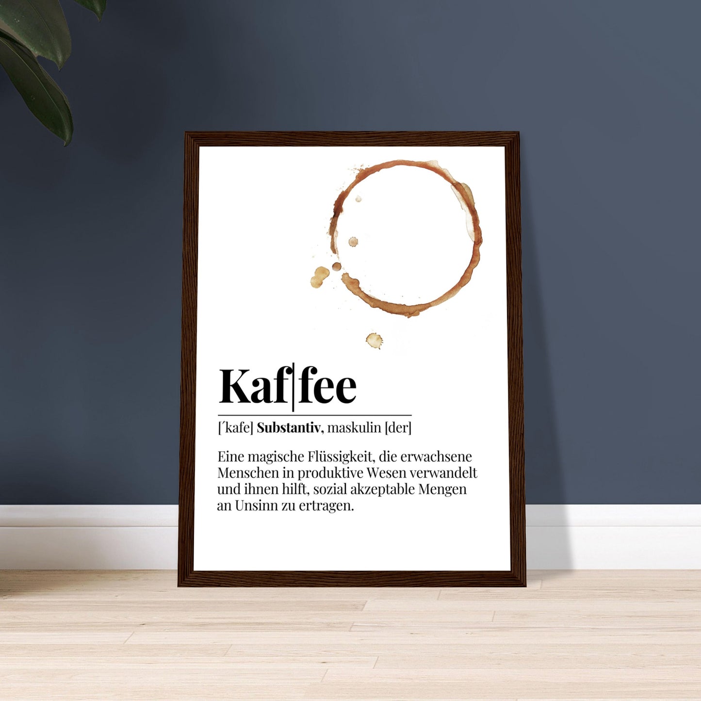 Ein Bild im Holzrahmen mit der Definition von Kaffee mit einem frechen Spruch als Definition. Mittig im Bild befindet sich ein Kaffee Tassenabdruck . Das Bild Steh auf dem Boden und ist an einer Wand angelehnt.