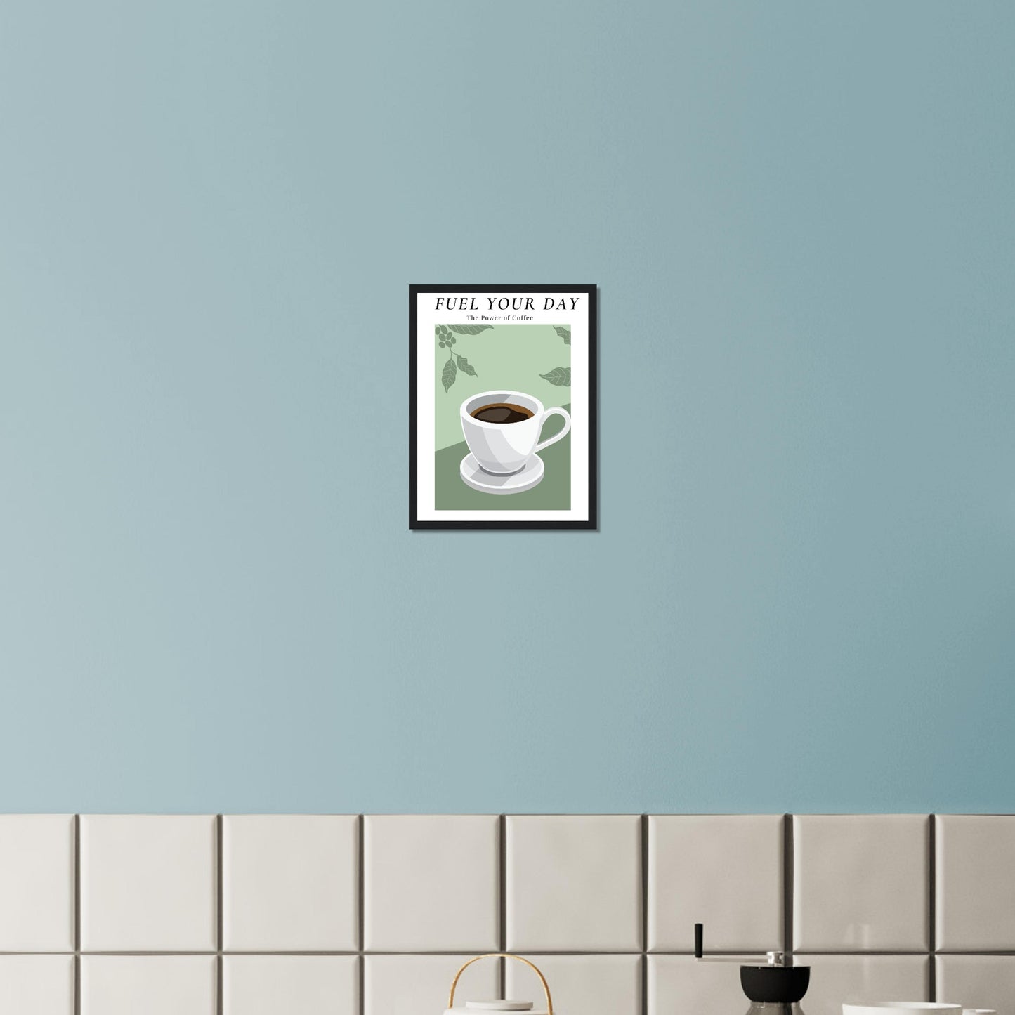 Ein Bild im Schwarzen Rahmen mit einer Tasse Kaffee auf einem Grünfarbigen Hintergrund mit Arabica Blätter als Akzente. Oben mittig des Bildes steht: "FUEL YOUR DAY" mit der Unterschrift "The Power of Coffee" über einer gefliesten Küchenwand.