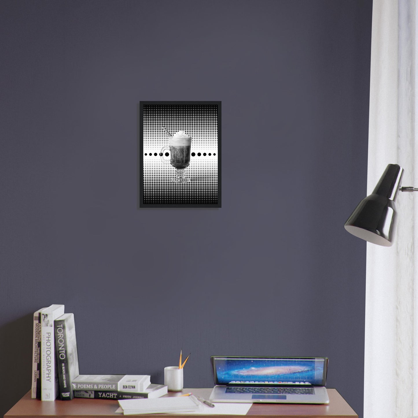 Bild im schwarzem Rahmen mit einem Schwarz weißem Motiv aus schwarzen punkten auf einem weißen Untergrund gepaart eines Schwarzweiß Foto eines Cappuccino über einem Schreibtisch an der Wand.