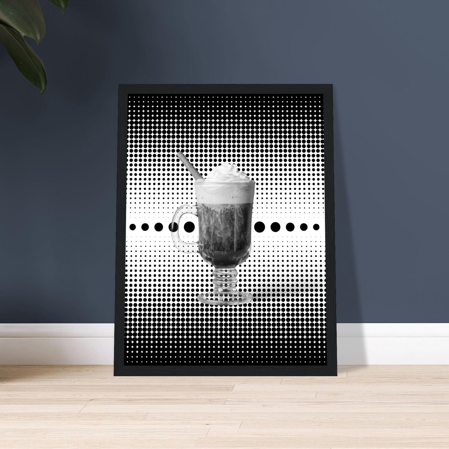 Bild im schwarzem Rahmen mit einem Schwarz weißem Motiv aus schwarzen punkten auf einem weißen Untergrund gepaart eines Schwarzweiß Foto eines Cappuccino auf dem Boden an der Wand angelehnt.